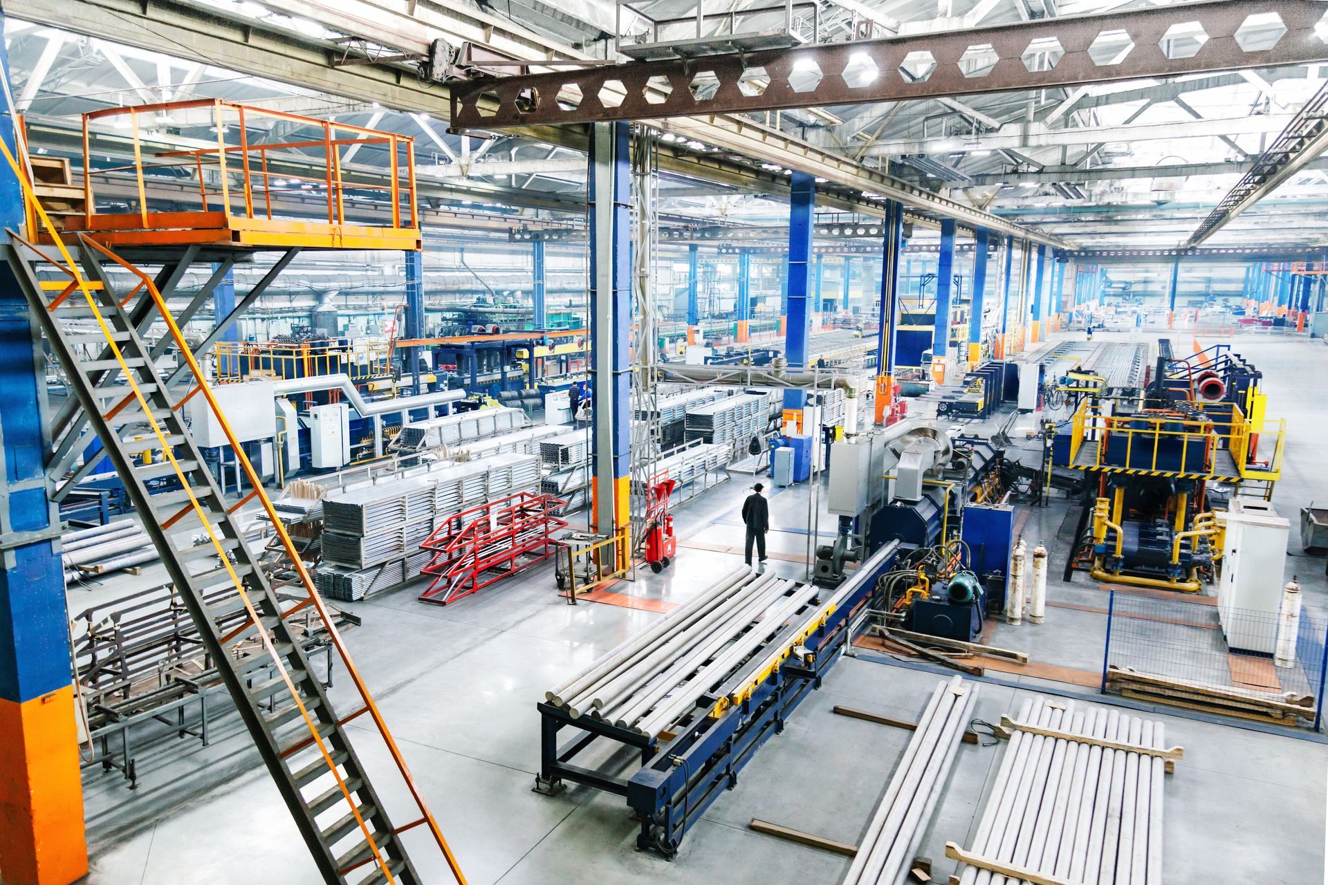 Atelier industriel avec machines, poutres métalliques et escalier dans un hall de production lumineux