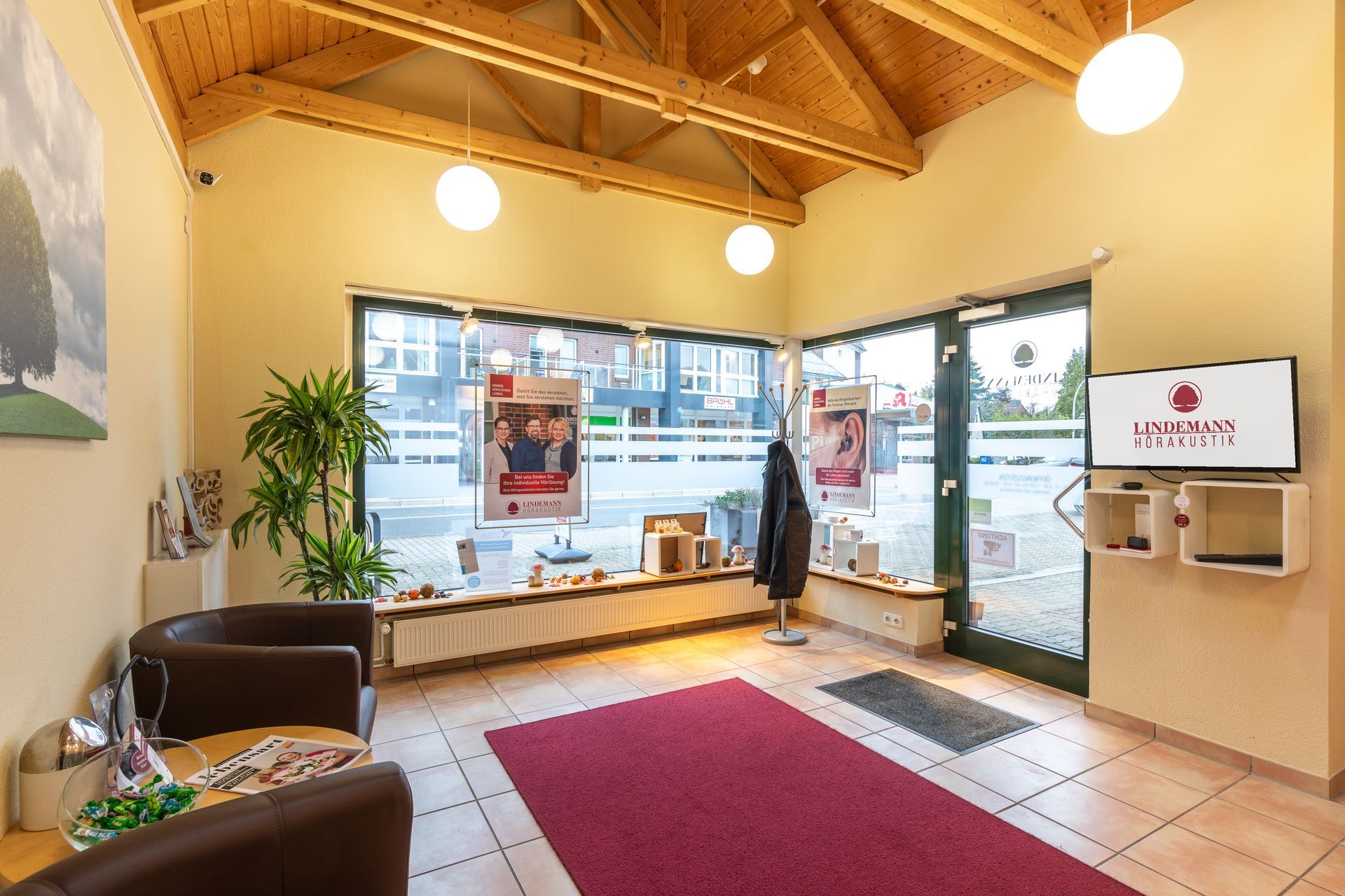 Ein Wartezimmer mit einem roten Teppich, Stühlen und einem Fernseher.