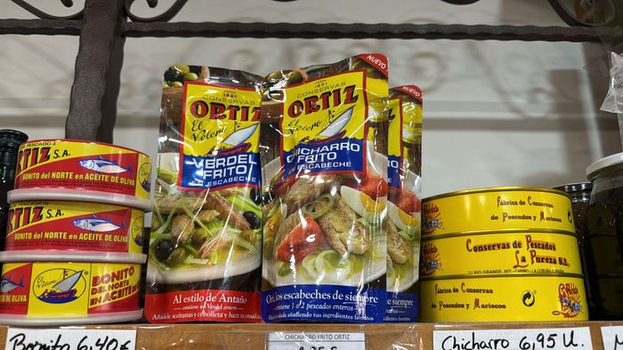 Un estante lleno de latas de atún y otros alimentos.