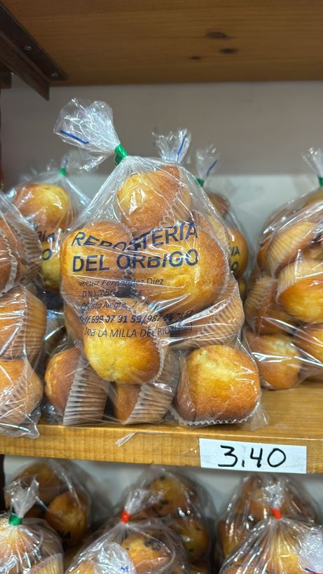 Un montón de muffins en bolsas de plástico en un estante de una panadería.