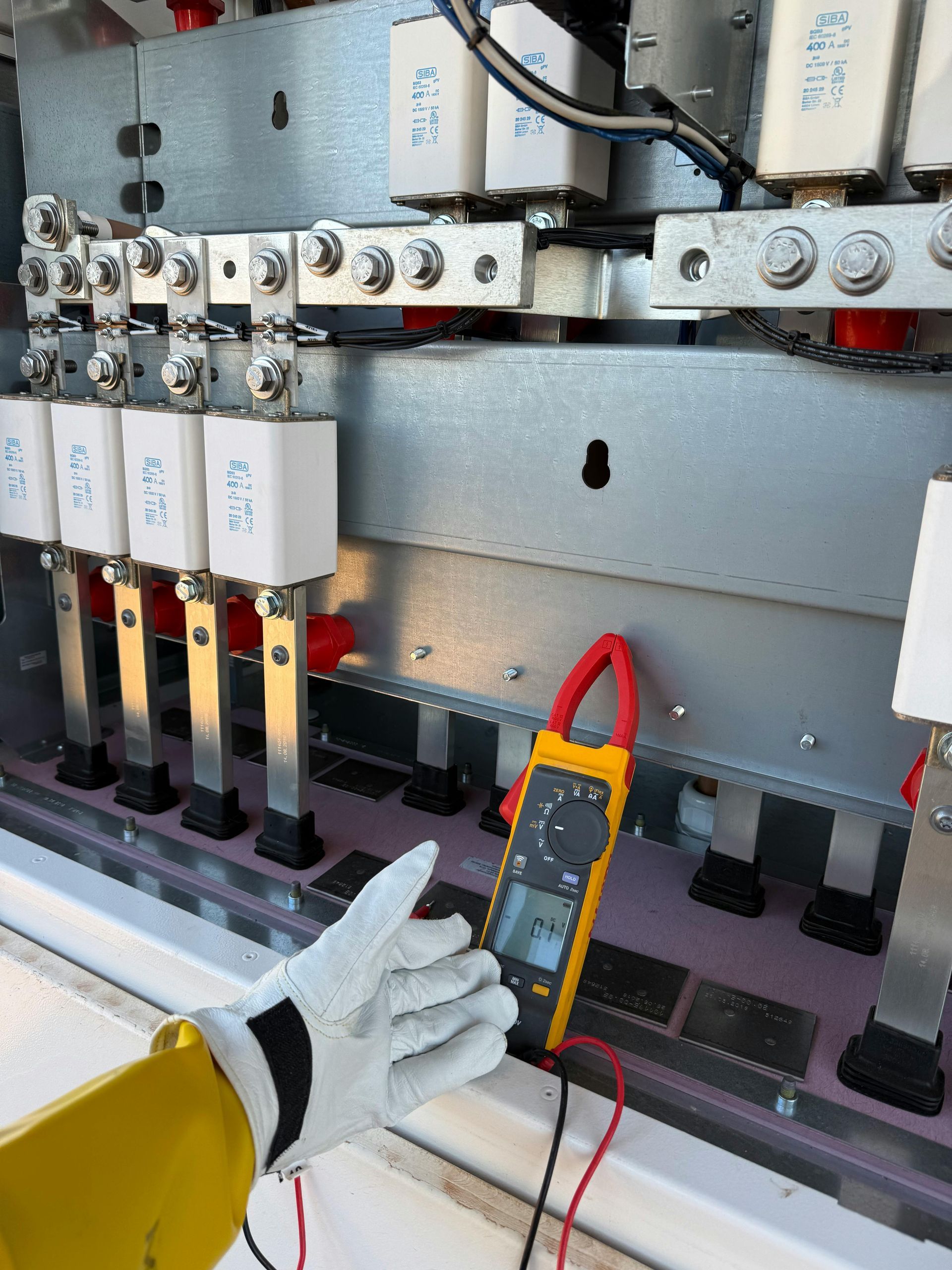 Un homme installe une prise électrique sur un mur carrelé à l'aide d'un tournevis.