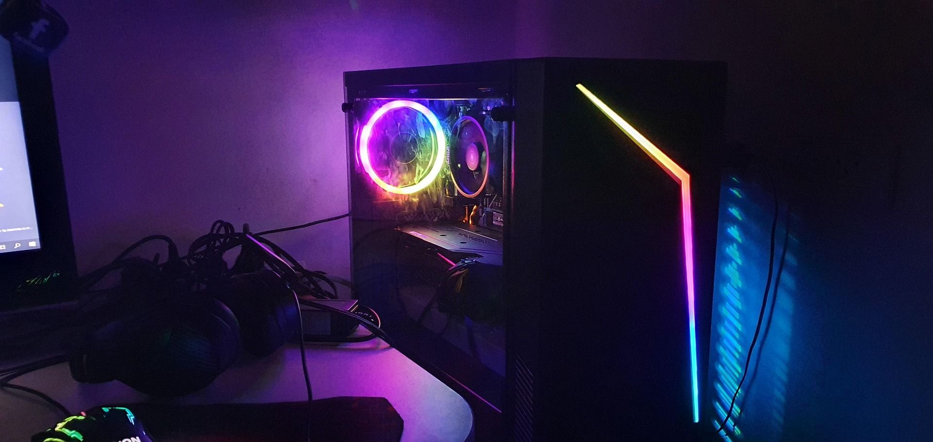 Tour d'ordinateur de bureau rétroéclairée RGB sur un bureau sombre dans une pièce faiblement éclairée de violet
