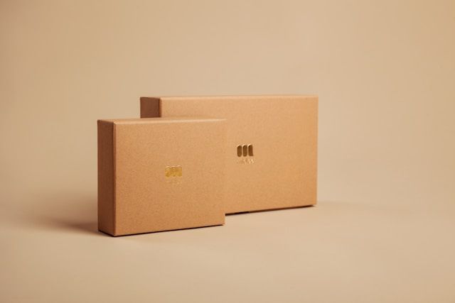 Deux boîtes en carton beige clair empilées sur une surface beige devant un fond beige uni