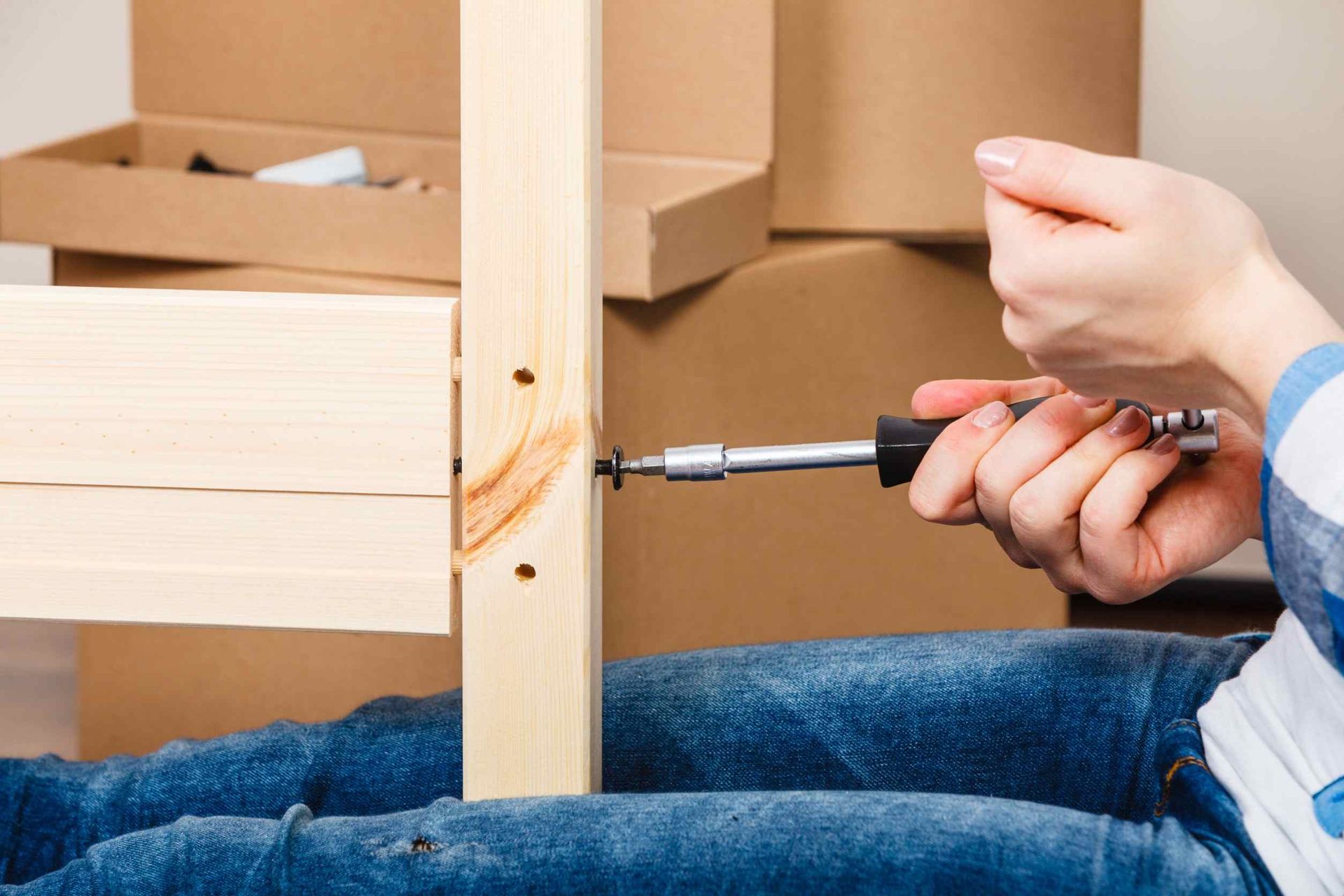 Una persona está usando un destornillador para atornillar un tornillo a un trozo de madera.