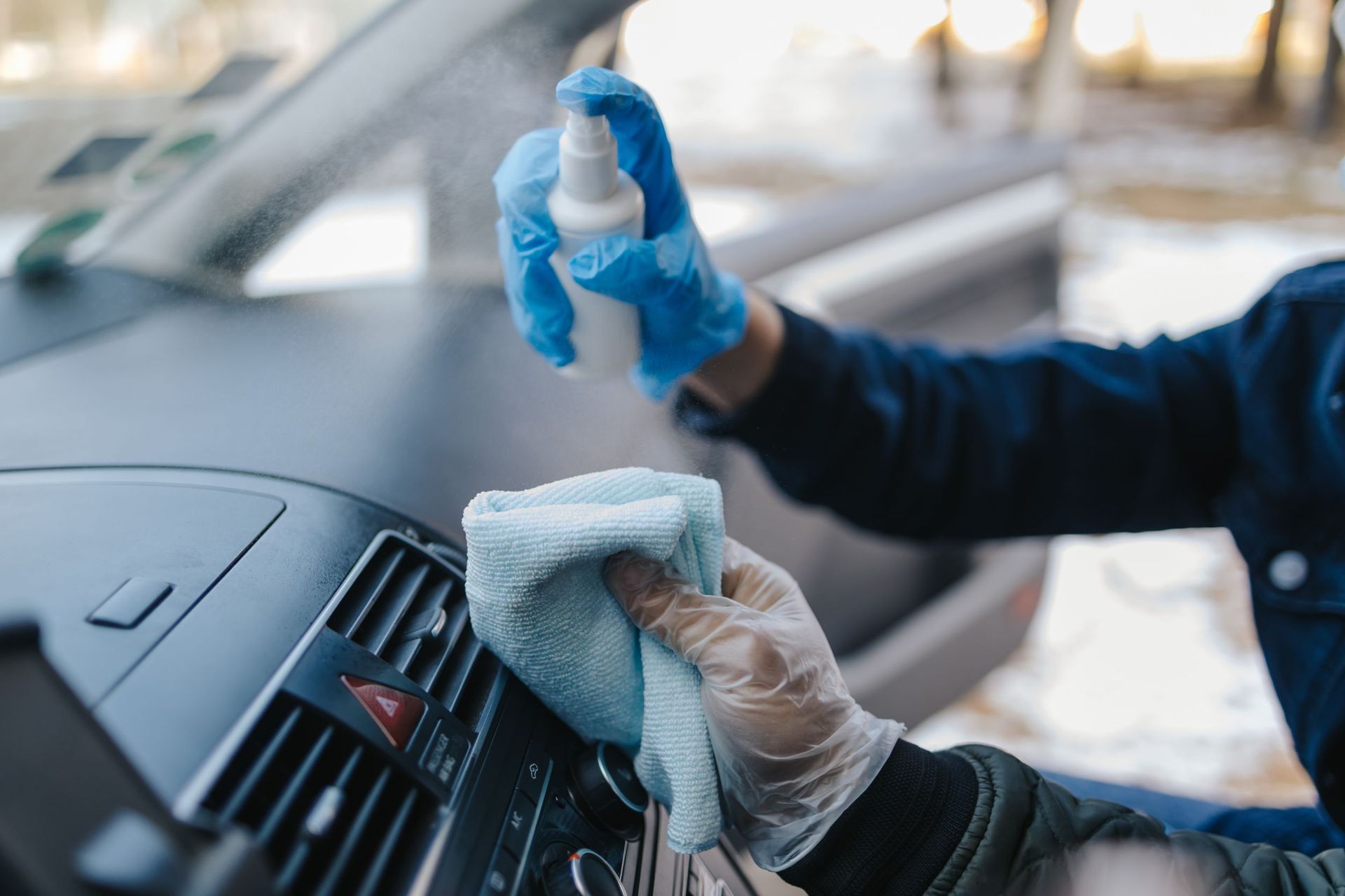 Una persona está limpiando el tablero de un automóvil con un paño y spray.