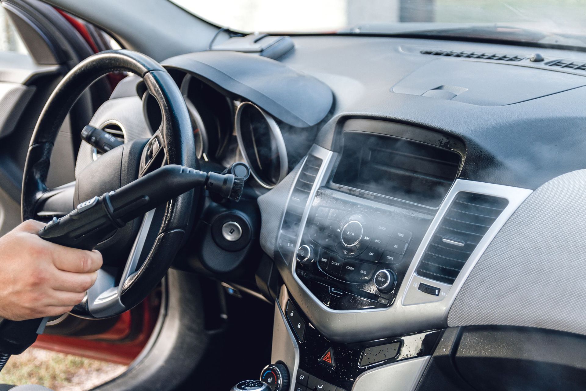 Una persona está limpiando el interior de un coche con una aspiradora.