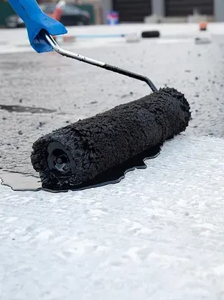 Una persona está pintando una superficie de hormigón con un rodillo.