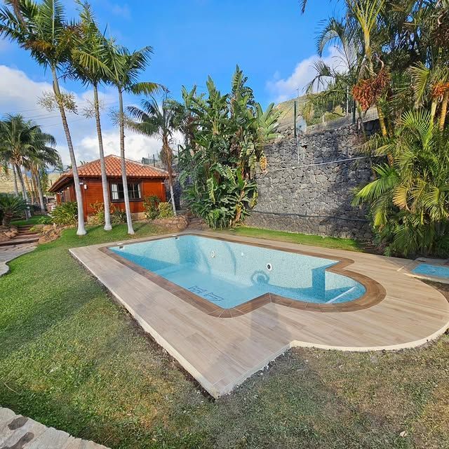 Una gran piscina rodeada de palmeras frente a una casa.
