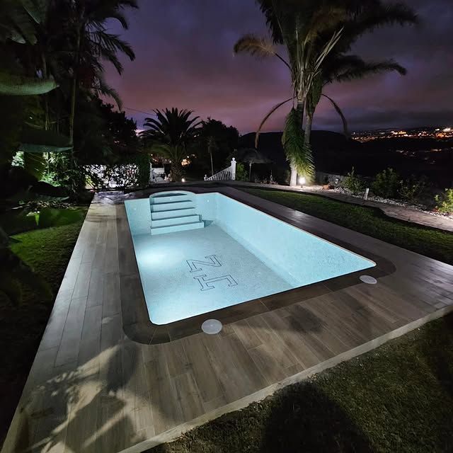 Una gran piscina está iluminada por la noche