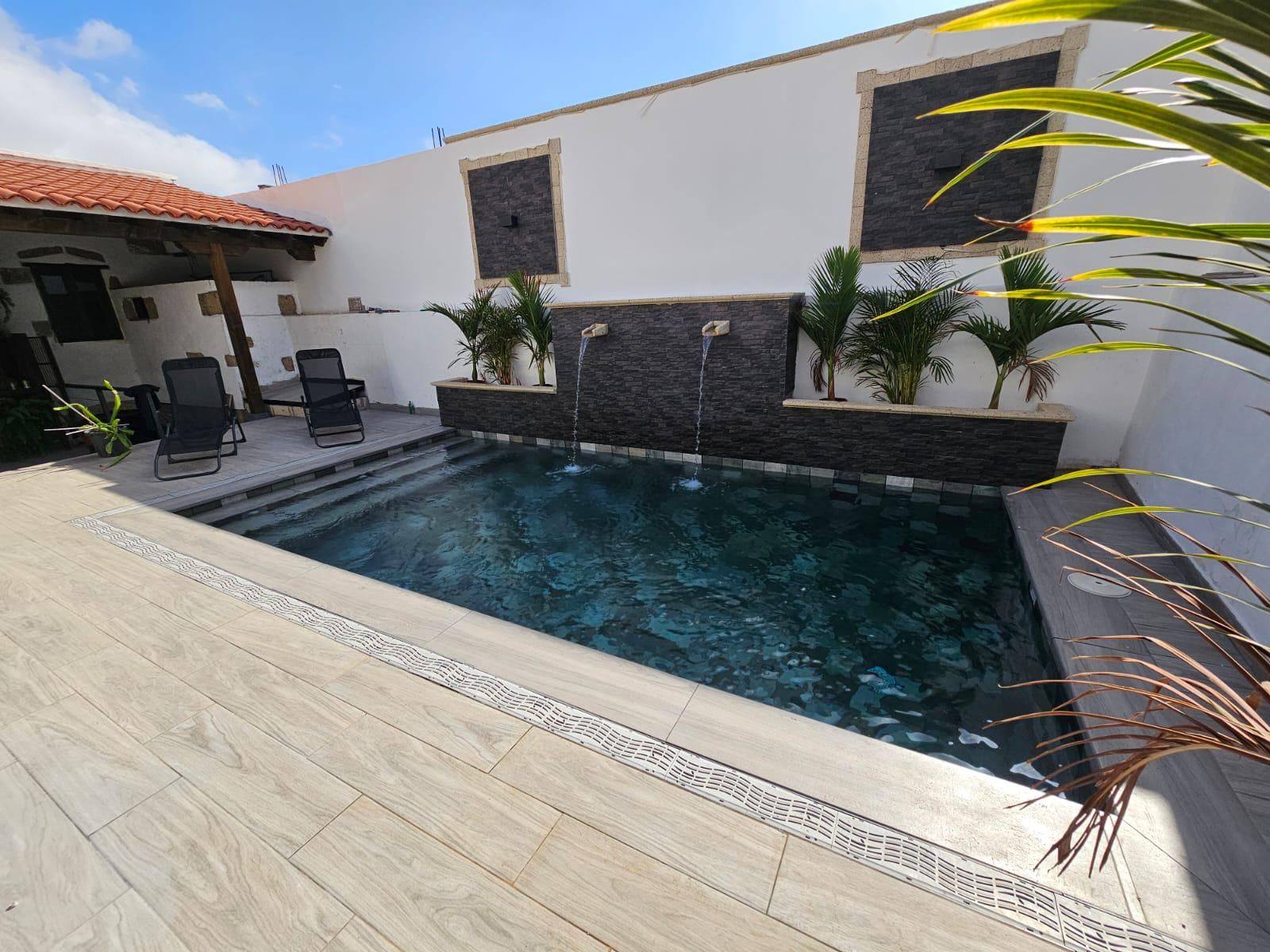 Una gran piscina con una fuente en el patio trasero de una casa.