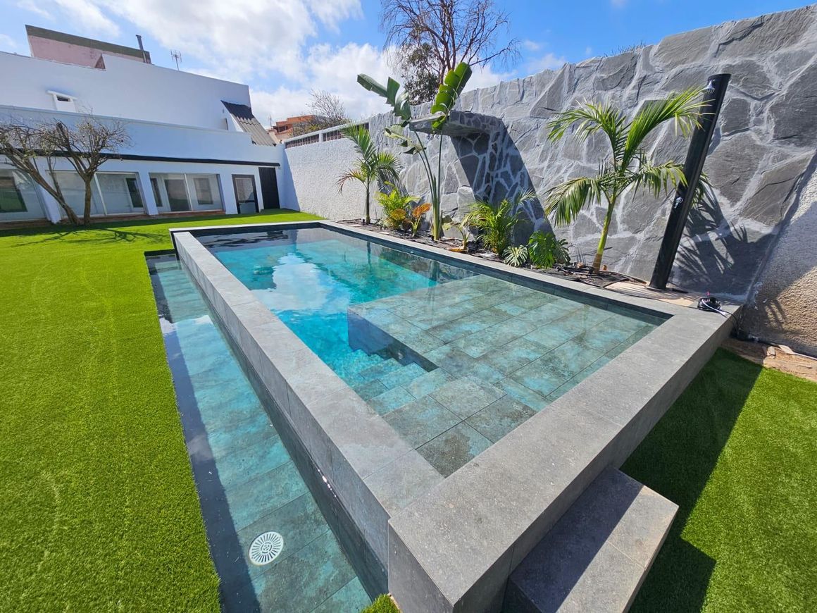 Una gran piscina está en el patio trasero de una casa.