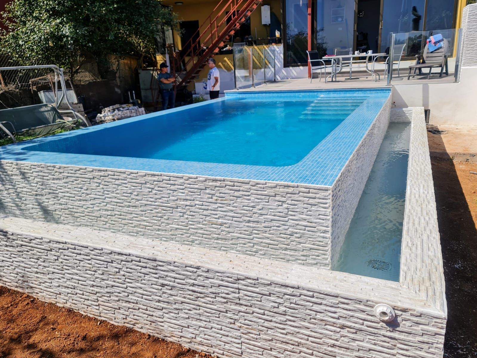 Se está construyendo una gran piscina en el patio trasero de una casa.