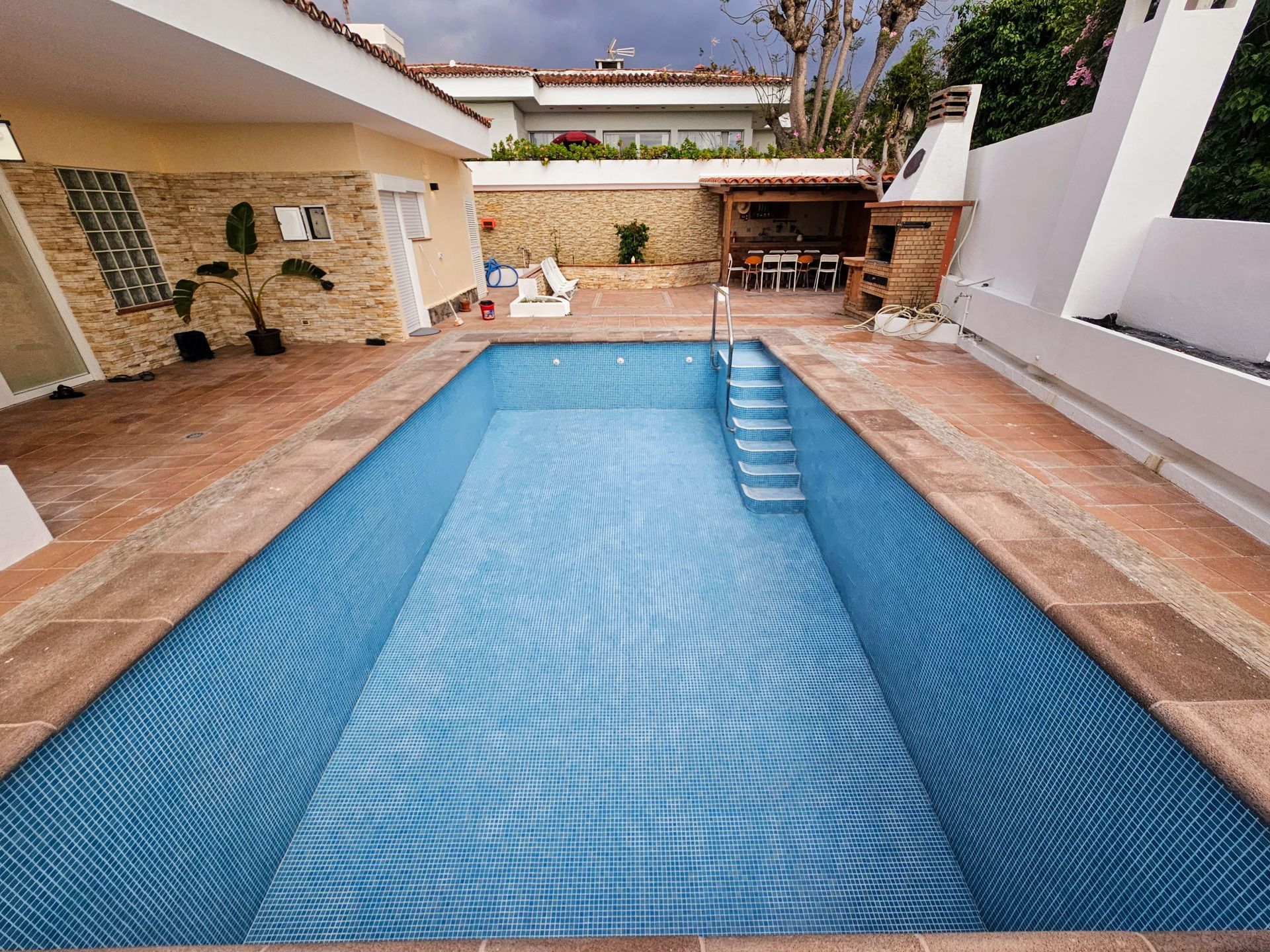 Una gran piscina está en el patio trasero de una casa.