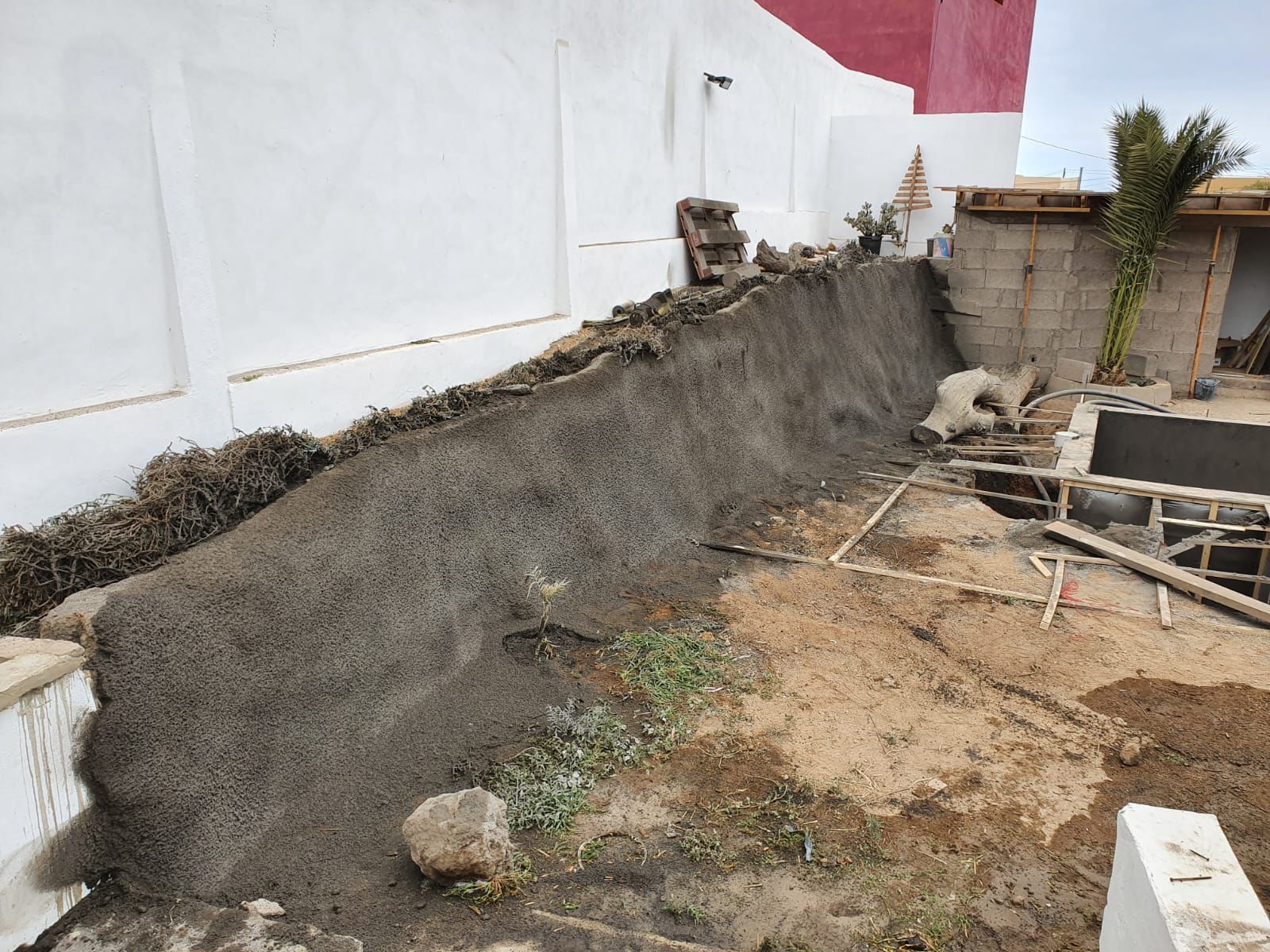 Un sitio de construcción con un talud de tierra cubierto con tela antierosión
