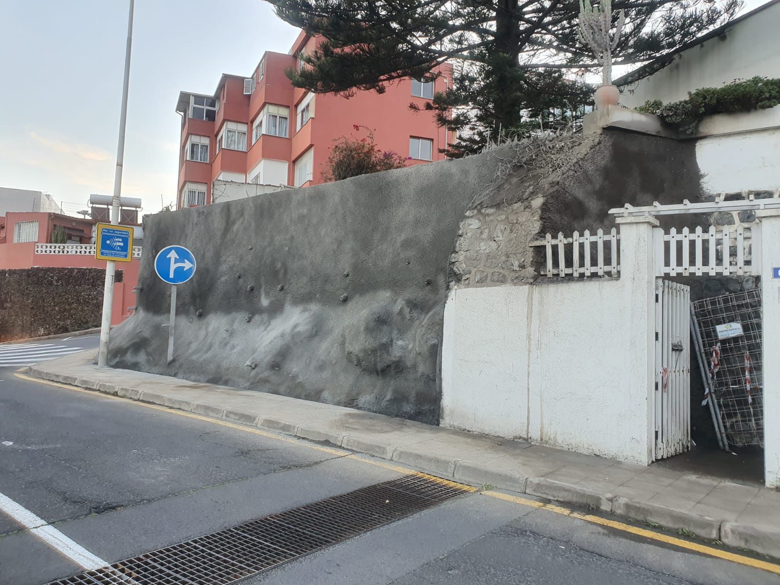 Un muro de hormigón desgastado con una señal de cruce de peatones, junto a una puerta blanca
