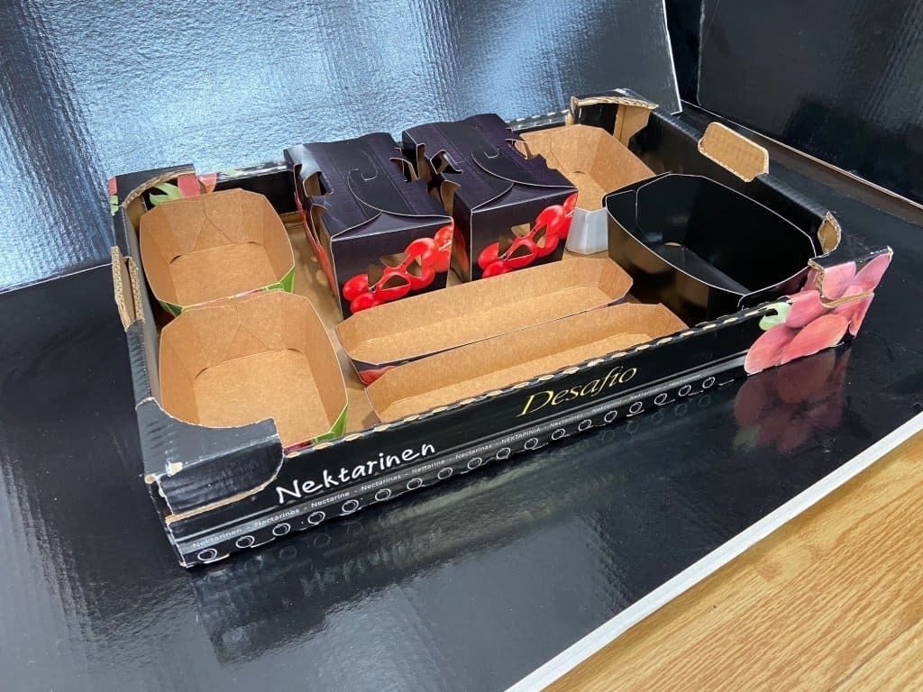 Una caja de cartón llena de cajas de fresas sobre una mesa.
