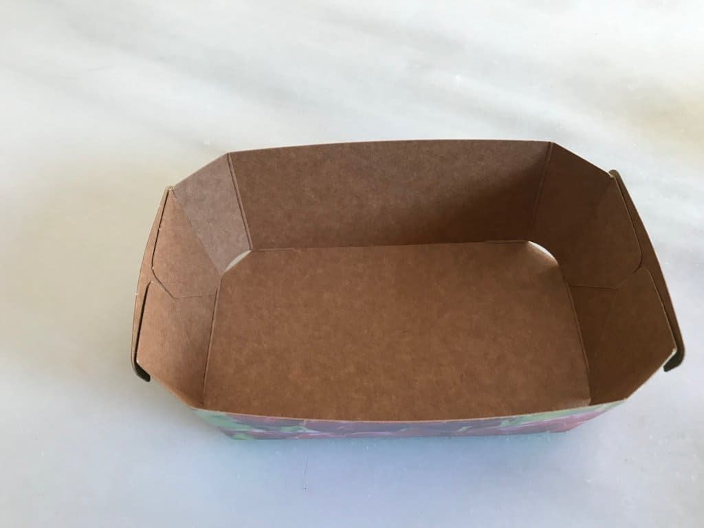 Una caja de cartón marrón está sobre una superficie blanca.