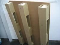 Una paleta de madera reposa en el suelo frente a una pared blanca.