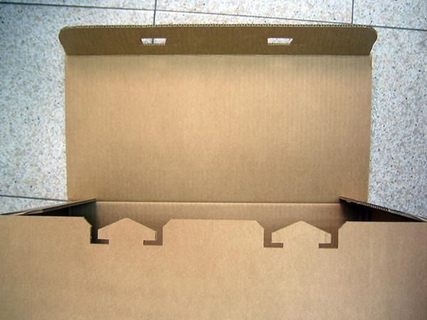 Una caja de cartón con la tapa abierta sobre un suelo de baldosas.