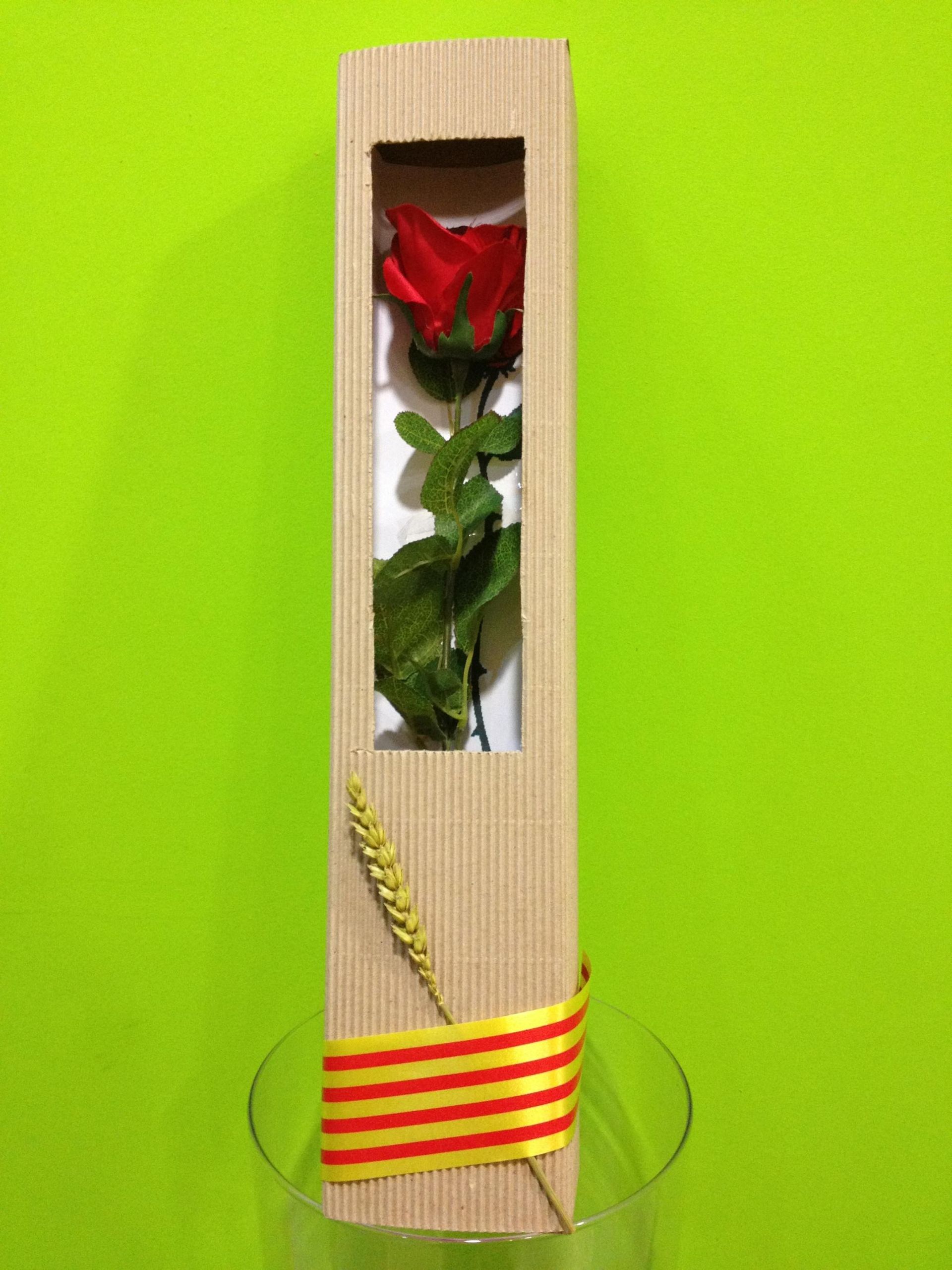 Una sola rosa roja en una caja de madera está sentada en un vaso.