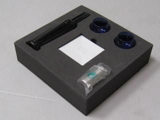 Una caja de espuma negra con un objeto negro dentro.