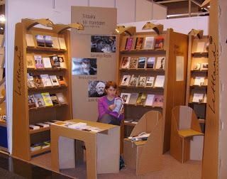 Una mujer está leyendo un libro en una librería de cartón.