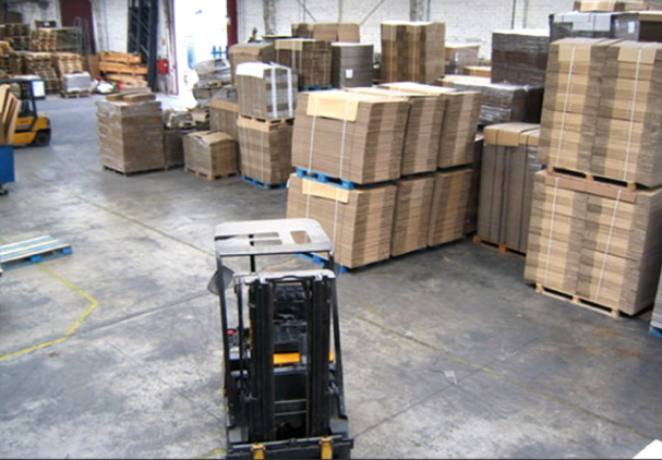 Un almacén lleno de cajas de cartón y una carretilla elevadora