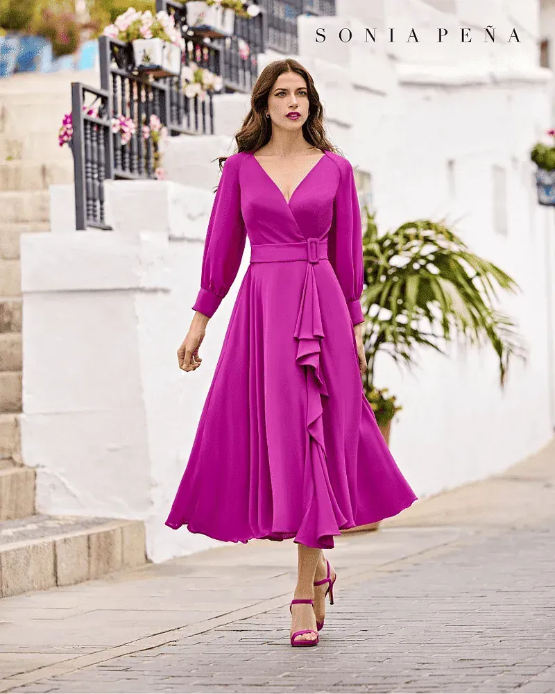 Una mujer con un vestido morado camina por una calle.