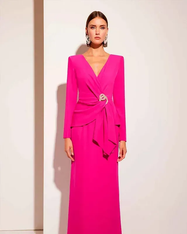 Una mujer lleva un vestido largo rosa con escote en V y mangas largas.