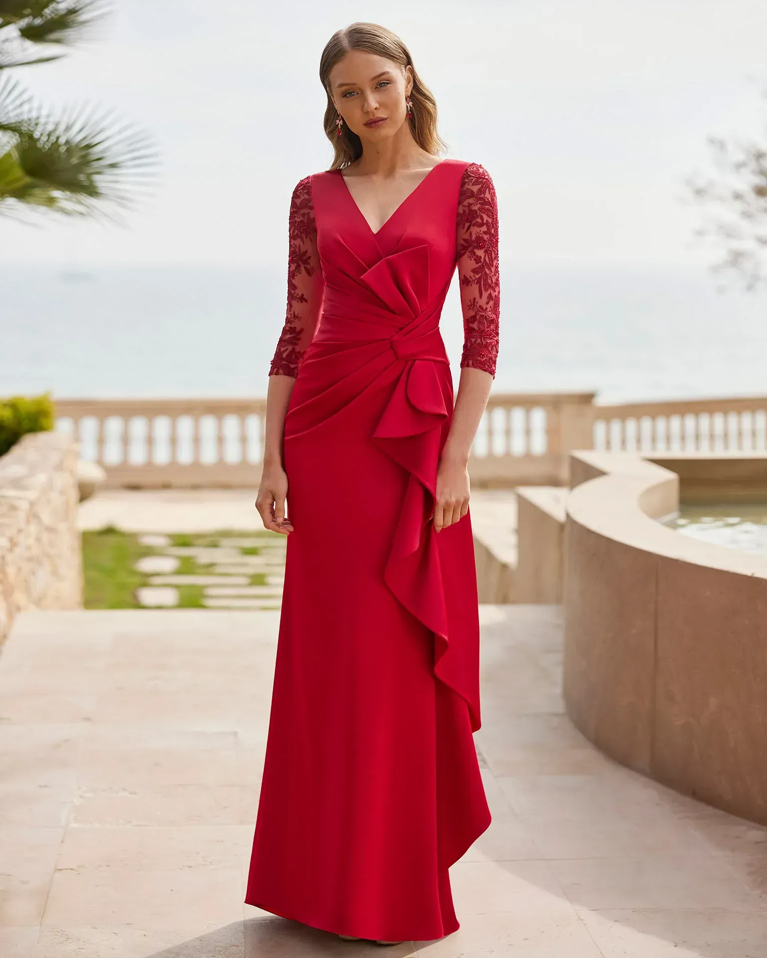 Una mujer lleva un vestido largo rojo con mangas de encaje.