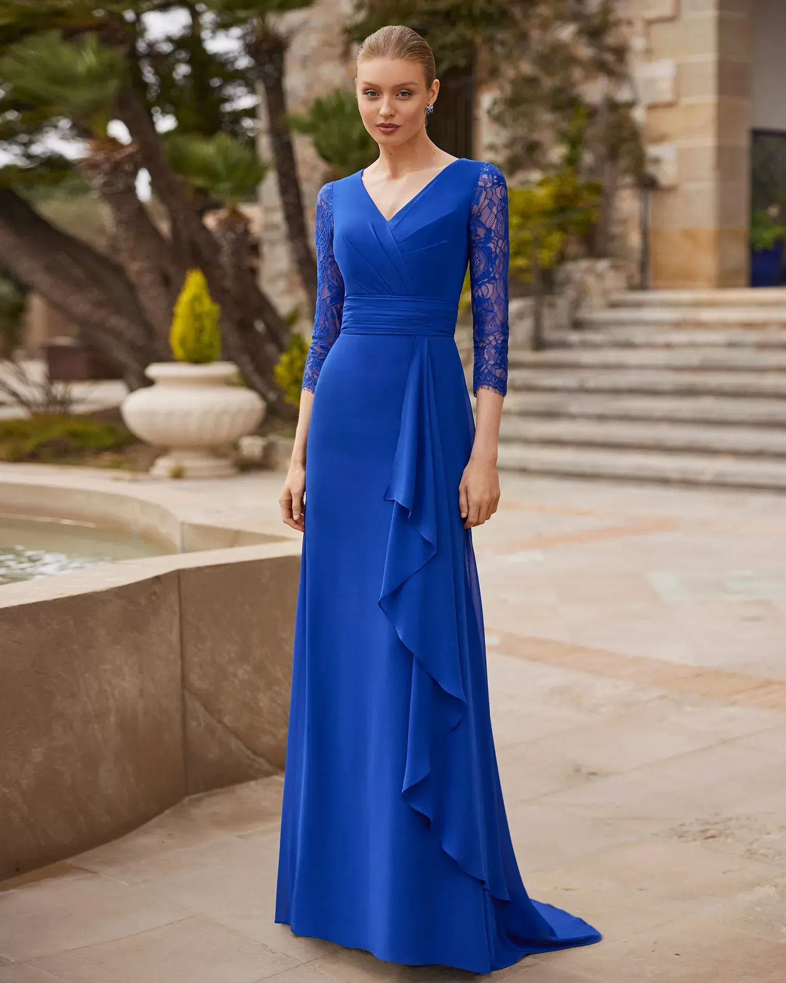 Una mujer lleva un vestido largo azul con mangas de encaje.