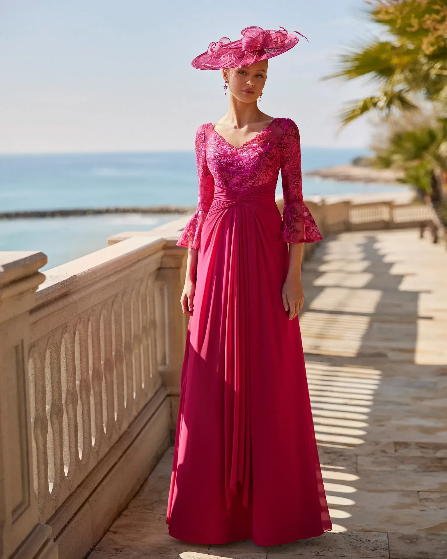 Una mujer lleva un vestido largo rosa y un sombrero rosa.