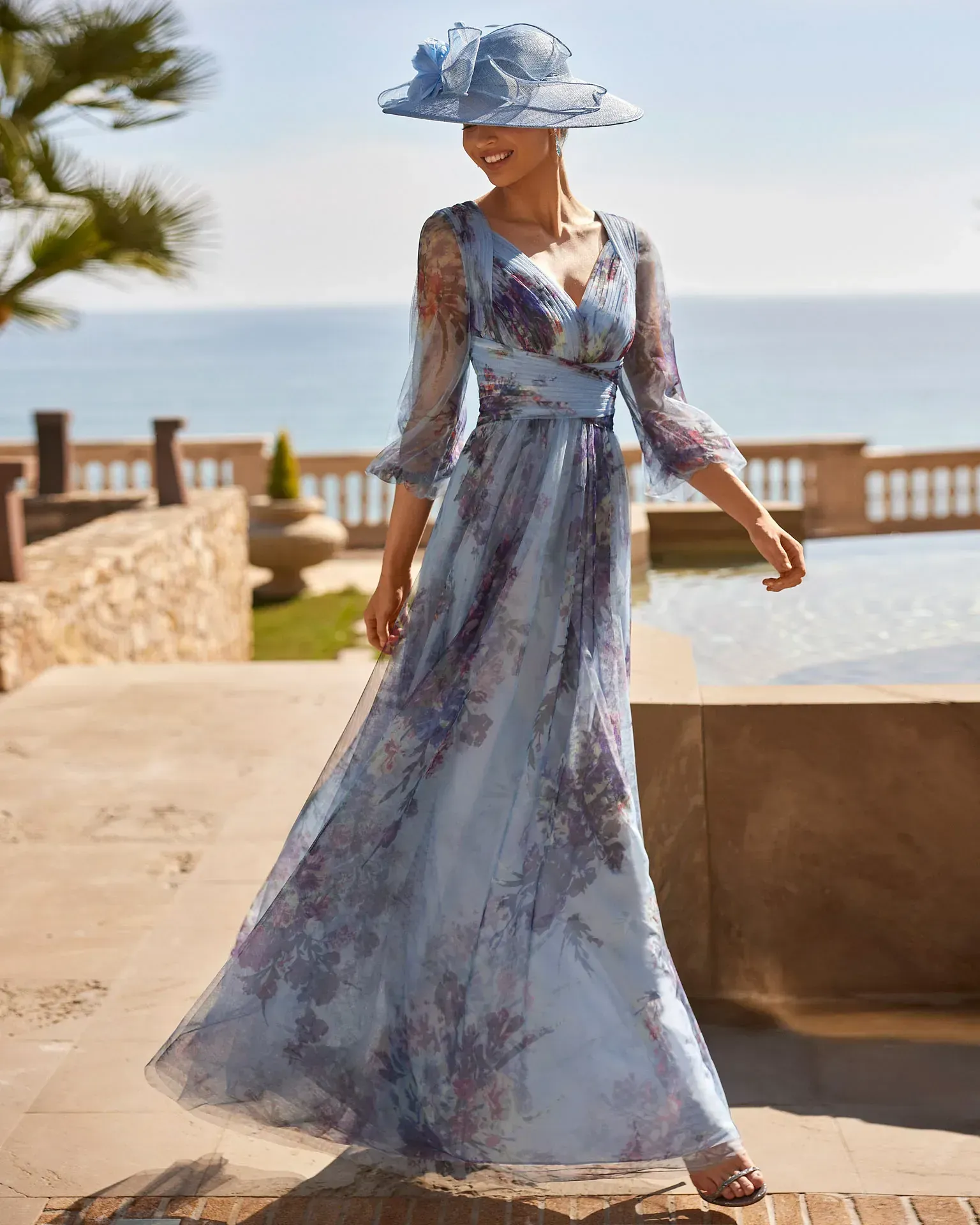 Una mujer lleva un vestido largo azul y un sombrero.