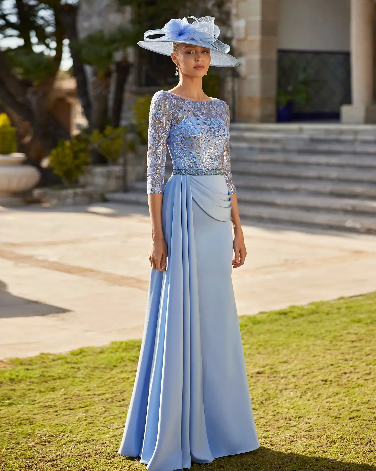 Una mujer lleva un vestido azul claro y un sombrero.
