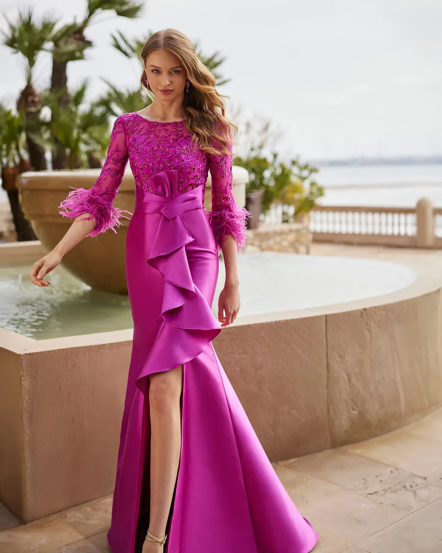 Una mujer con un vestido morado está parada frente a una fuente.