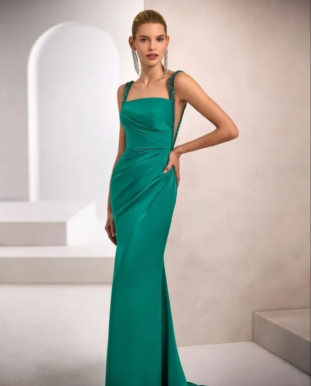 Mujer con un vestido de noche color turquesa posando en un estudio minimalista.