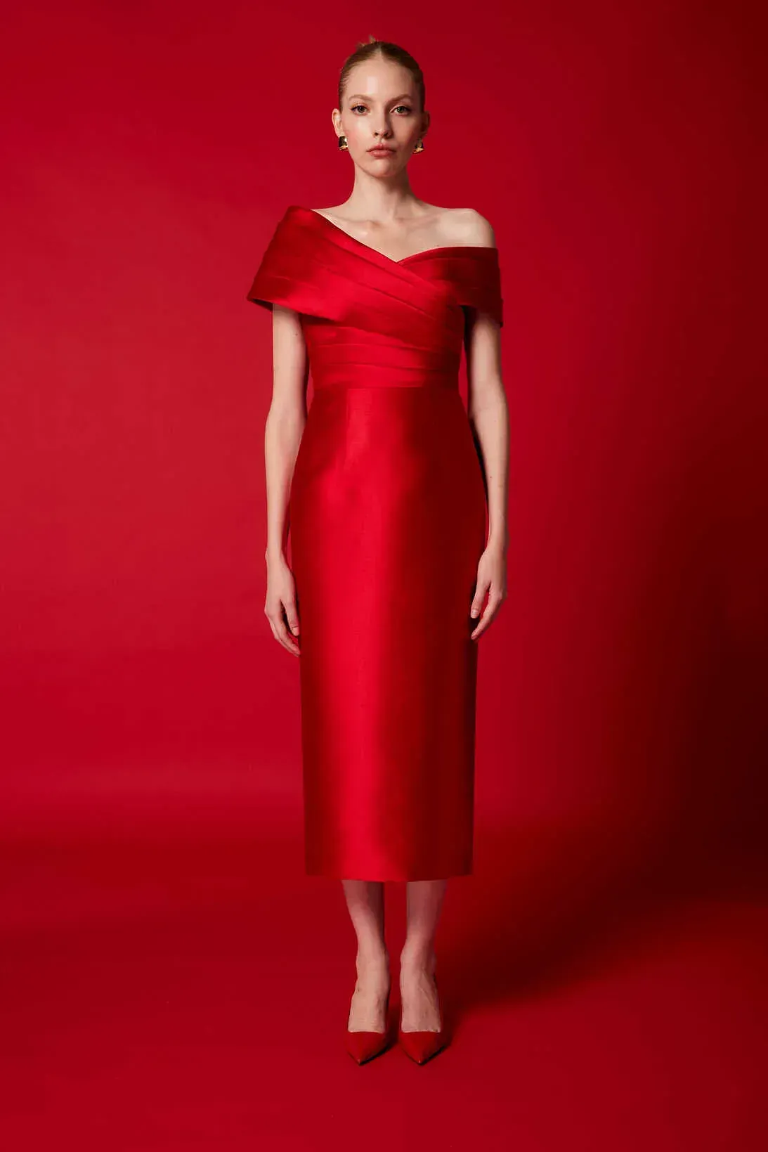 Una mujer lleva un vestido rojo con hombros descubiertos y zapatos rojos.