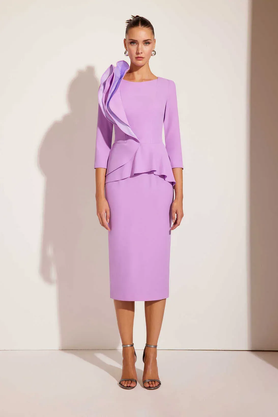 Una mujer lleva un vestido morado con un volante en el lateral.