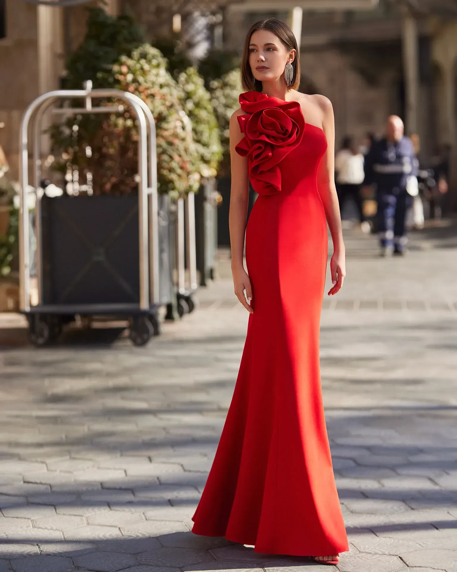 Una mujer con un vestido rojo está parada en una acera.