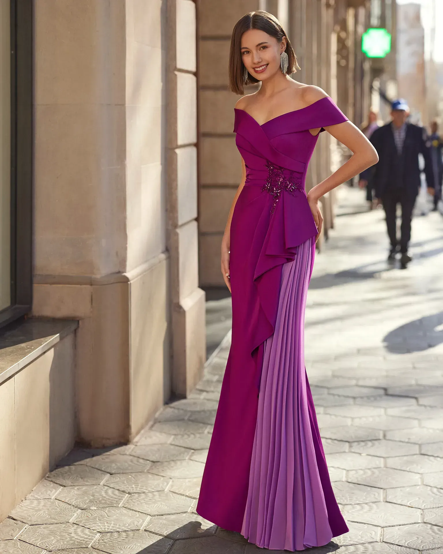 Una mujer con un vestido morado está parada en una acera.