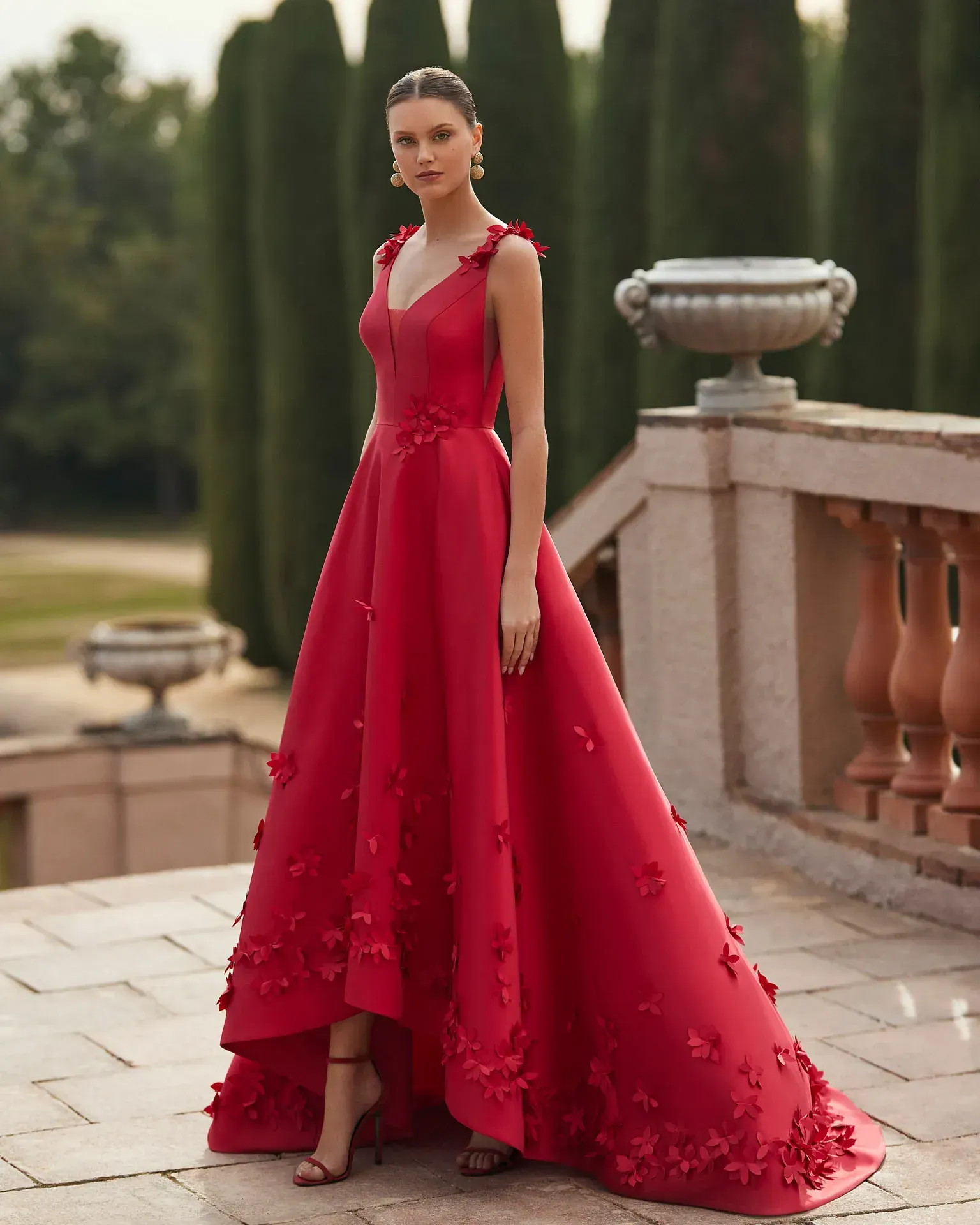 Una mujer con un vestido rojo está parada en un balcón.