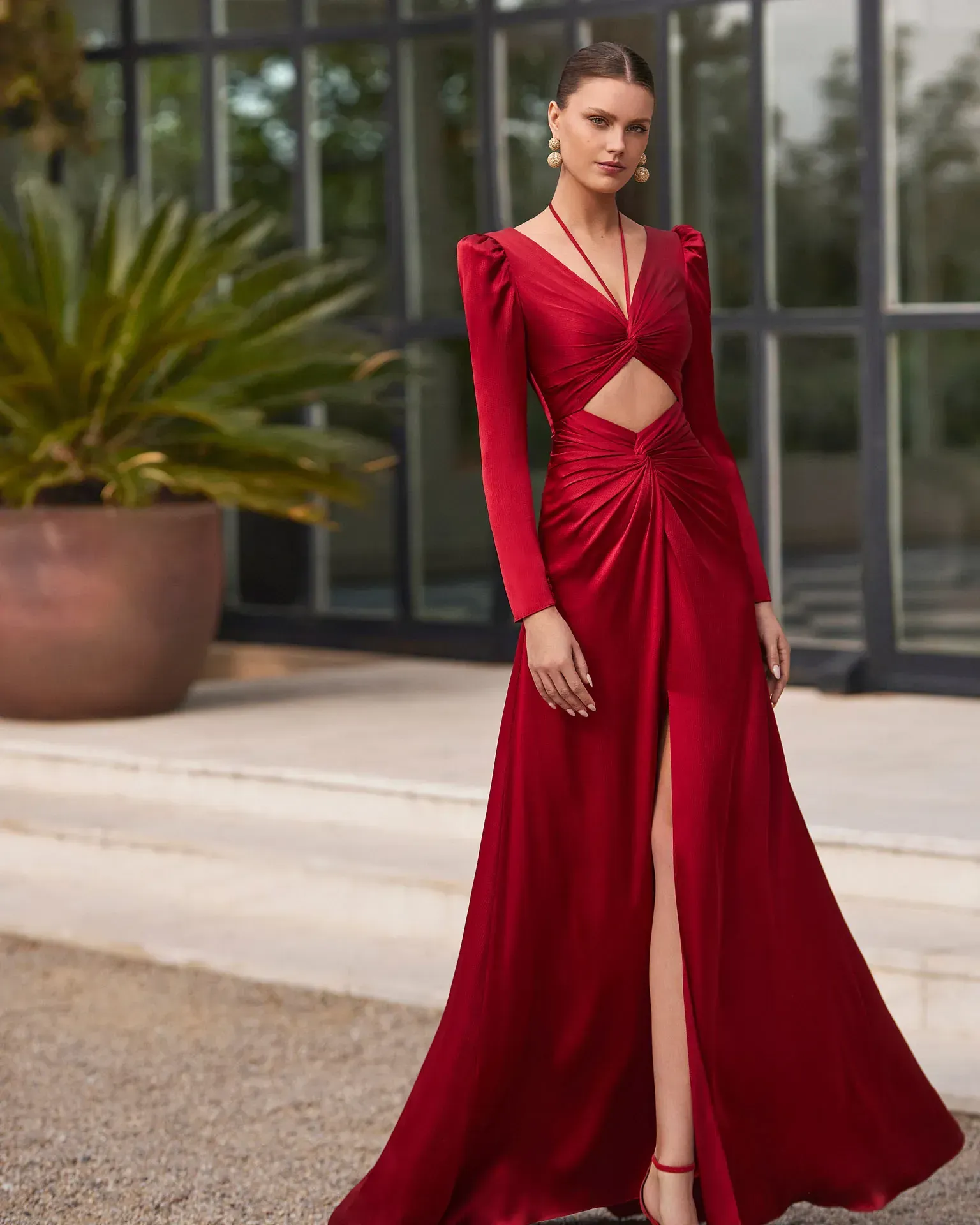 Una mujer con un vestido largo rojo está parada frente a un edificio.