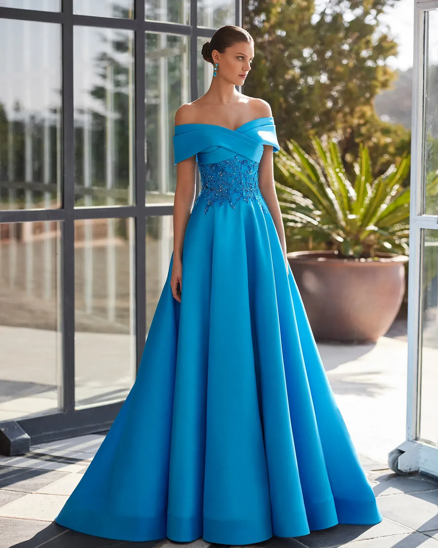 Una mujer lleva un vestido azul con hombros descubiertos.