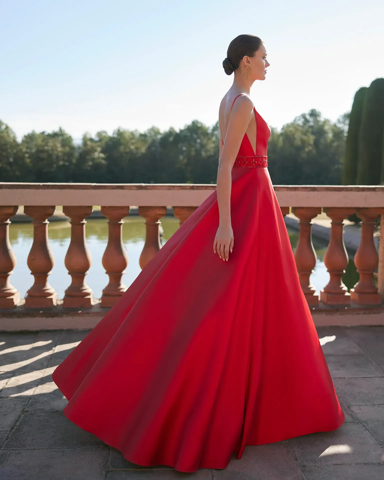 Una mujer con un vestido rojo está parada frente a un lago.