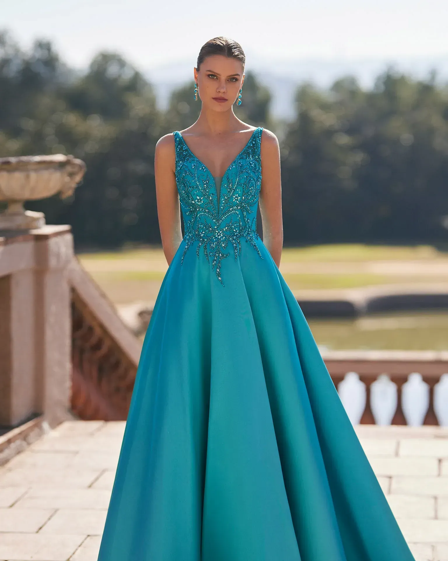 Una mujer con un vestido largo azul está parada en un balcón.