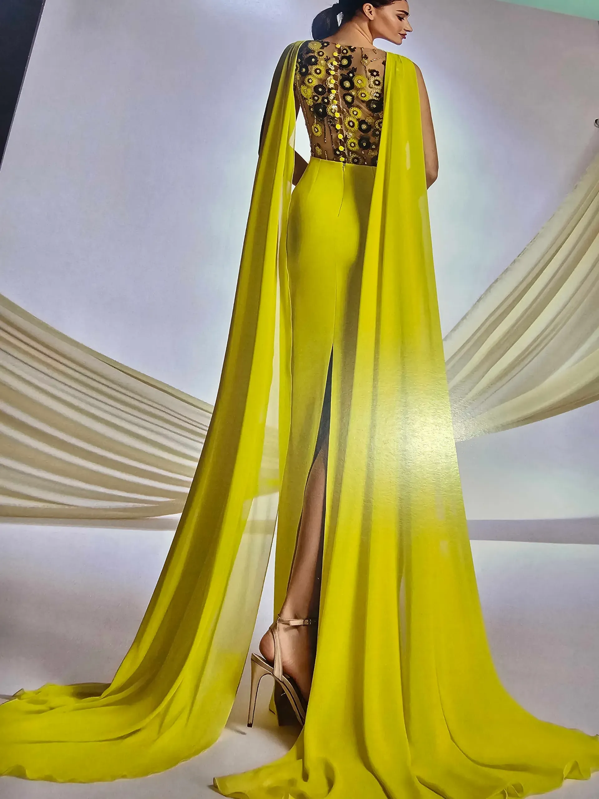 Una mujer con un vestido largo amarillo y una capa