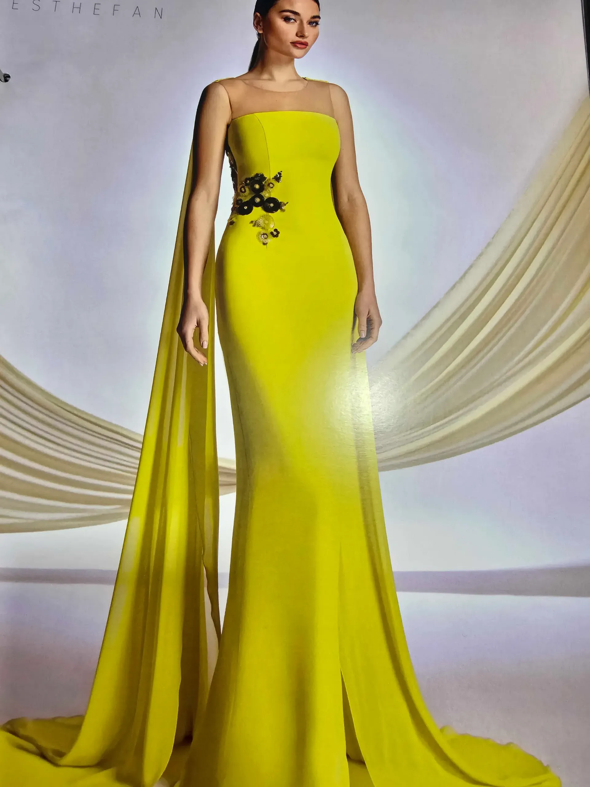 Una mujer con un vestido largo amarillo y una capa