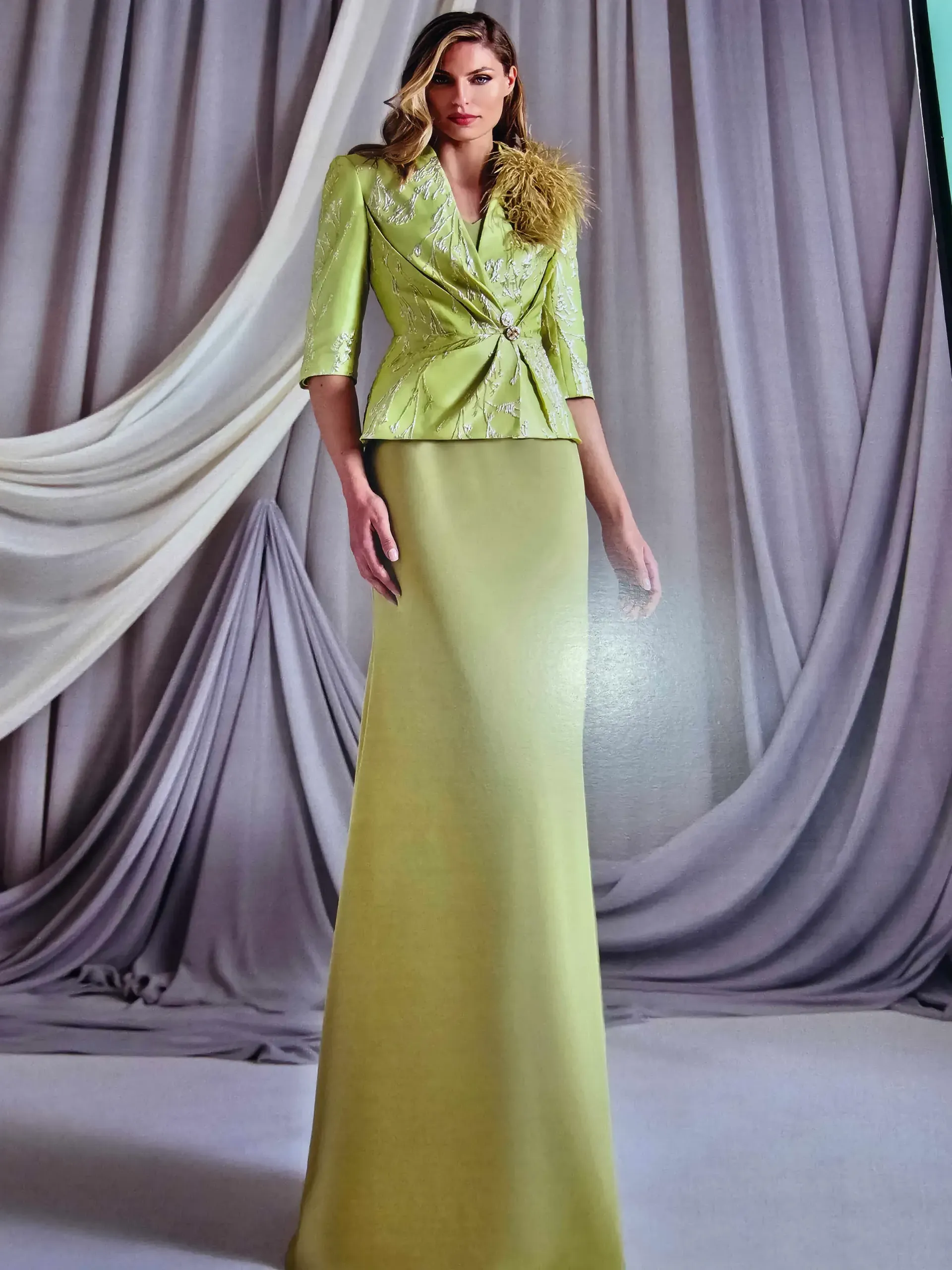 Una mujer lleva un vestido largo verde y una chaqueta verde.