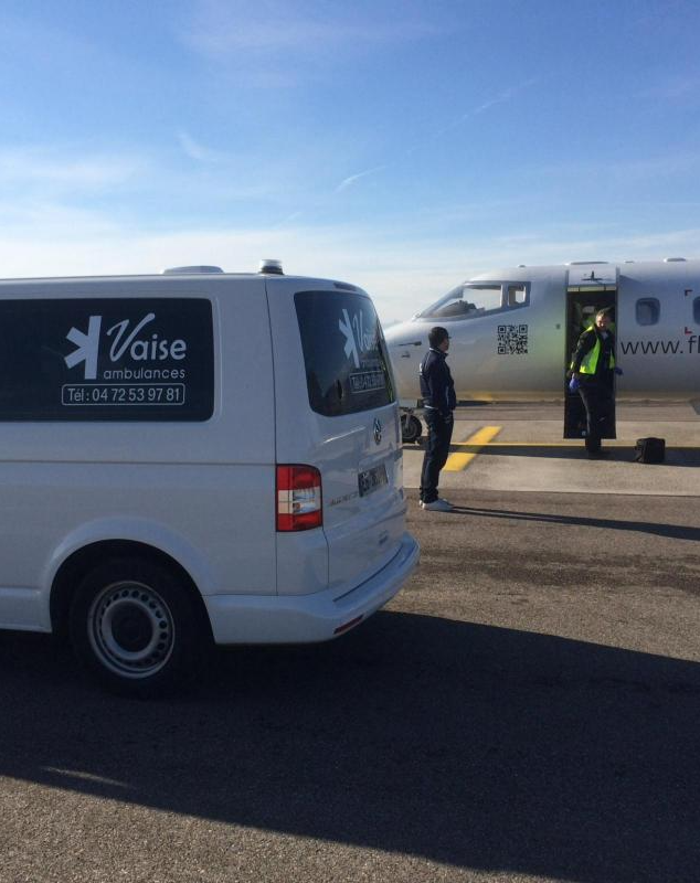 Ambulance de l'entreprise Vaise Ambulances à côté d'un avion dans l'aéroport