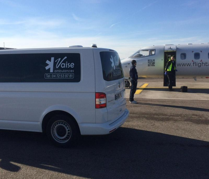 Ambulance de l'entreprise Vaise Ambulances à côté d'un avion dans l'aéroport